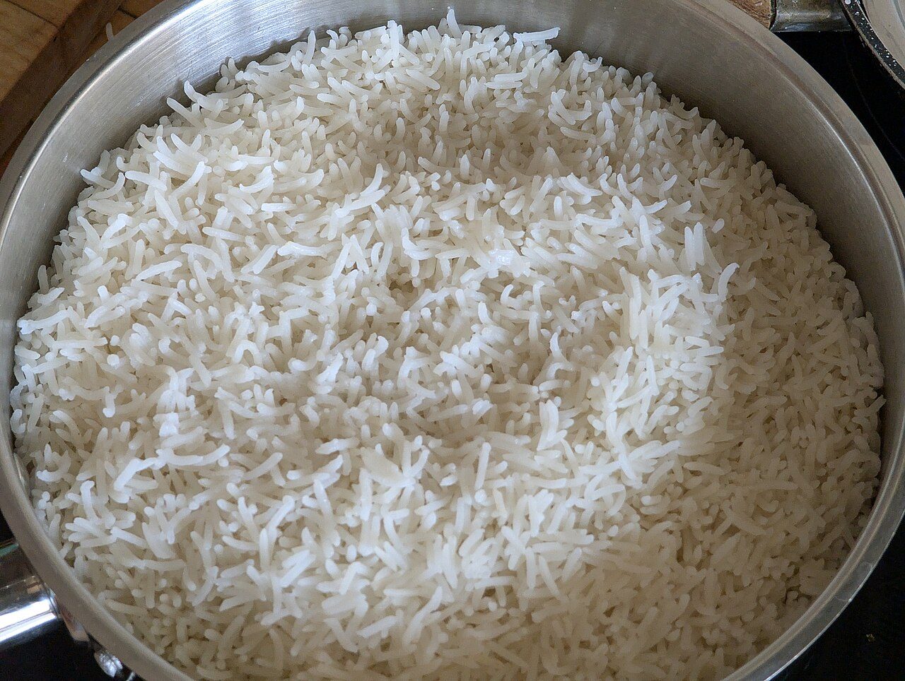 Arroz basmati branco cozido numa panela de inox, com os grãos longos e separados
