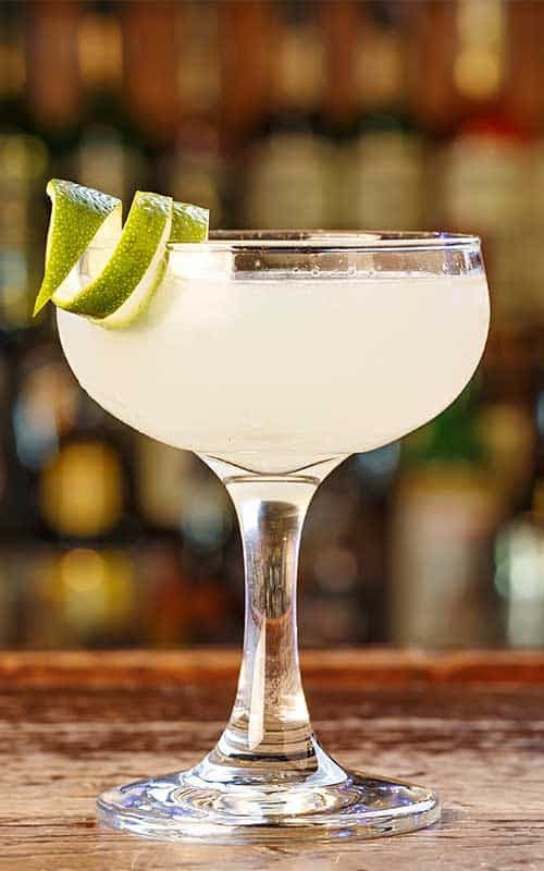 Daiquiri clássico em taça coupe com casca de limão, no balcão de um bar