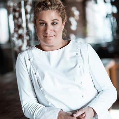 Chef Ana Roš de dólmã branco, sorrindo de leve no salão do restaurante