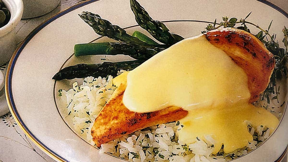 Peito de frango grelhado coberto com molho supreme, servido com arroz e aspargos