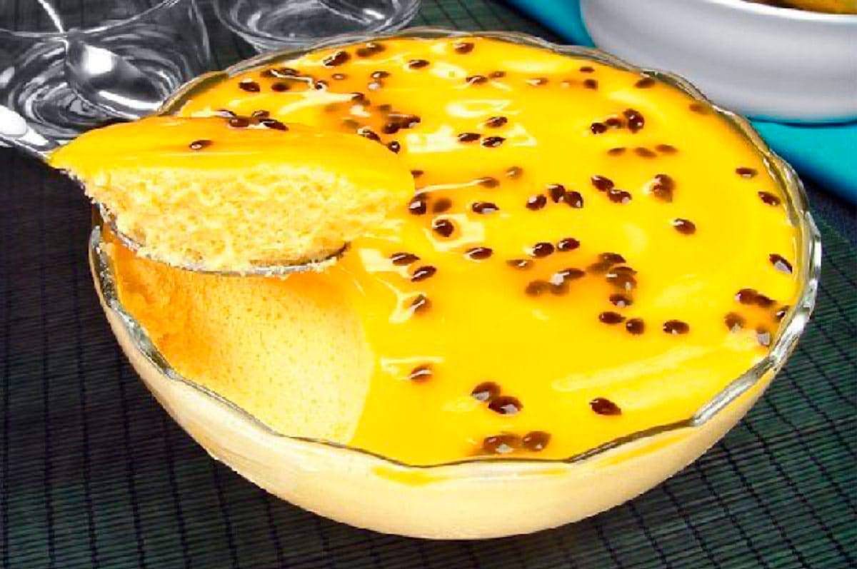Musse de maracujá com calda e sementes numa tigela de vidro, com uma porção na colher