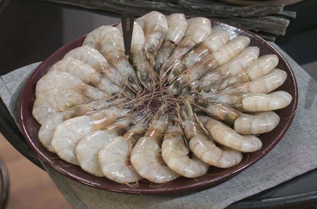 Camarão branco cru com casca arrumado em círculo num prato redondo